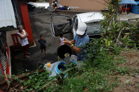 A resident affected by Hurricane Maria pours water delivered into a holding tank outside his home in the Trujillo Alto municipality outside San Juan, Puerto Rico, October 9, 2017. REUTERS/Shannon Stapleton