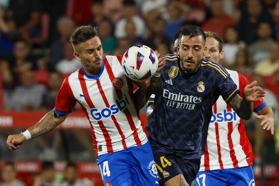 FILE - Girona's Aleix Garcia, left, duels for the ball with Real Madrid's Joselu during a Spanish La Liga soccer match between Girona and Real Madrid, at the Montilivi stadium in Girona, Spain, Saturday, Sept. 30, 2023. Girona’s chief executive was hoping at the start of the season that his team could simply avoid relegation from Spanish soccer's top tier. So Ignasi Mas-Baga tells The Associated Press that he is surprised as anyone to see the team from the northeast corner of Spain leading the standings a third of the way through the season. (AP Photo/Joan Monfort, File)