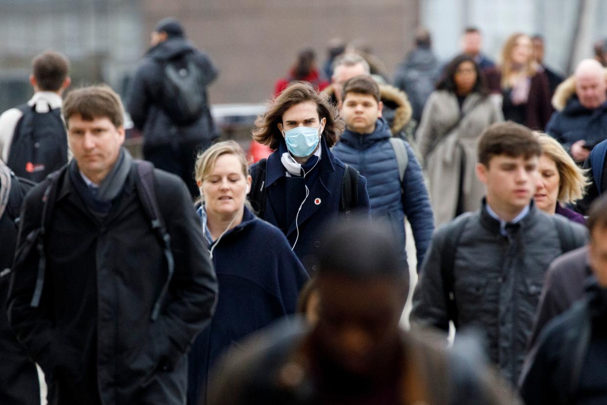 A commuter wears a mask whilst walking across London Bridge into the City of London during the morning rush hour on March 18, 2020 as people take precautions amid the coronavirus outbreak. - The British government will on Wednesday unveil a raft of emergency powers to deal with the coronavirus epidemic, including proposals allowing police to detain potentially infected people to be tested. (Photo by Tolga AKMEN / AFP) (Photo by TOLGA AKMEN/AFP via Getty Images)