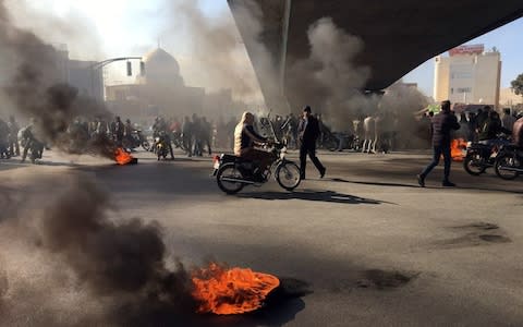 Iranian protesters block a highway following fuel price increase in Tehran - Credit: STRINGER/EPA-EFE/REX