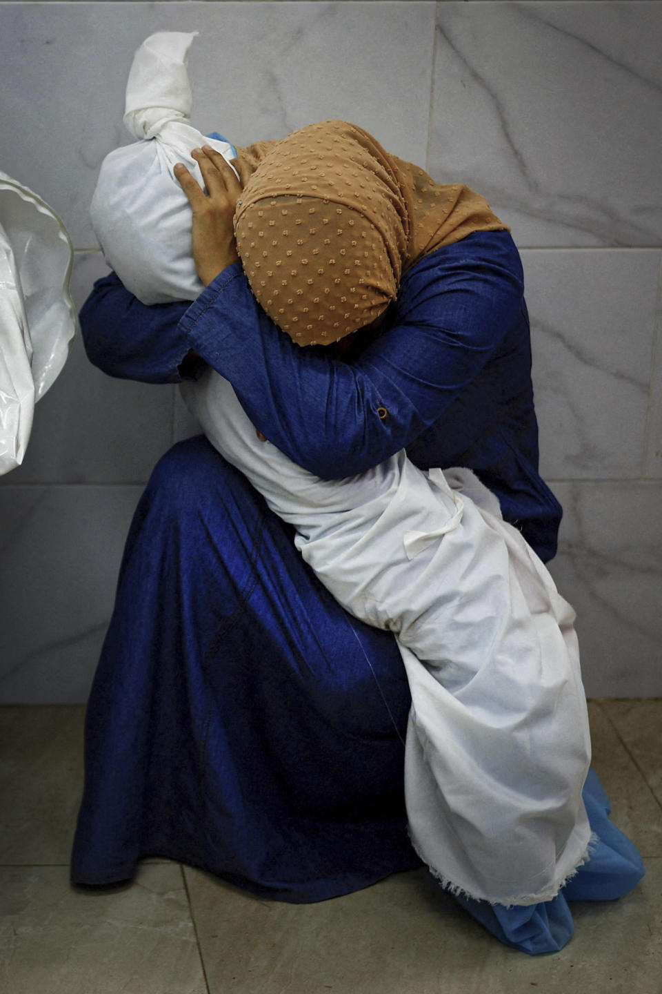 This image provided by World Press Photo and taken by Mohammed Salem of the Reuters news agency won the World Press Photo Award of the Year and shows Palestinian woman Inas Abu Maamar, 36, embracing the body of her 5-year-old niece Saly, who was killed in an Israeli strike, at Nasser hospital in Khan Younis in the southern Gaza Strip, October 17, 2023. (Mohammed Salem/Reuters/World Press Photo via AP)