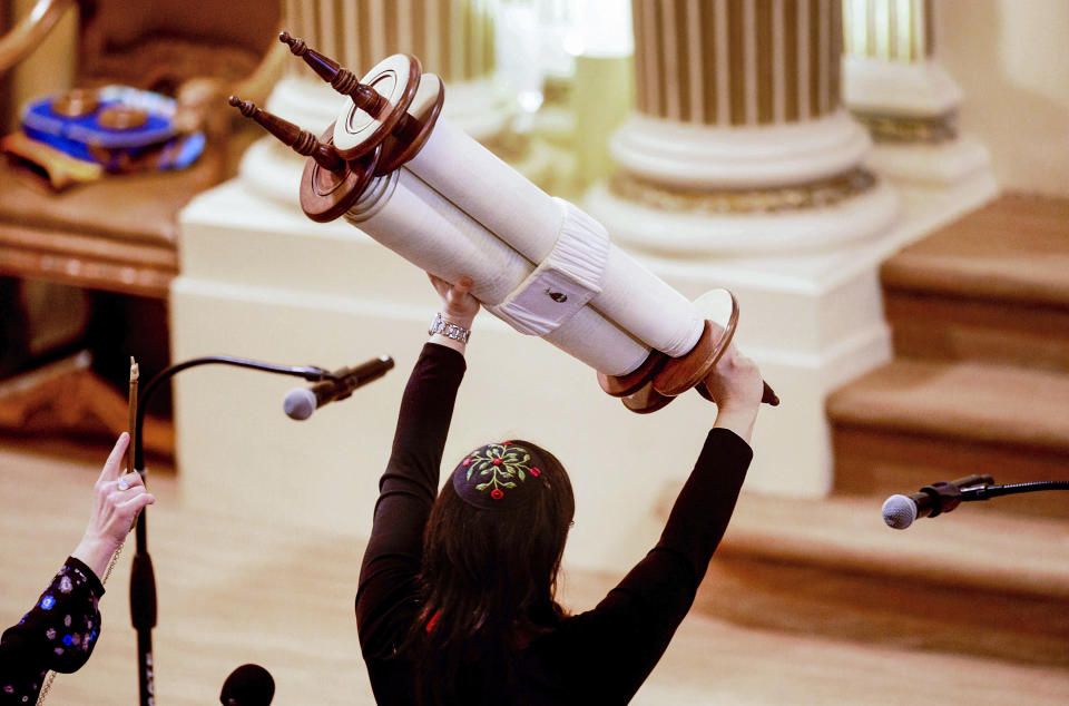 FILE - In this Feb. 1, 2020, file photo, Rabbi Jacqueline Mates-Muchin holds a Torah scroll aloft during Shabbat morning service at Temple Sinai in Oakland, Calif. The California Department of Public Health released Monday, May 25, a framework under which county health departments can approve the reopening of churches, mosques, synagogues and other houses of worship that have mostly shuttered their doors since Gov. Gavin Newsom’s March stay-at-home order designed to slow the spread of the coronavirus. (AP Photo/Noah Berger, File)