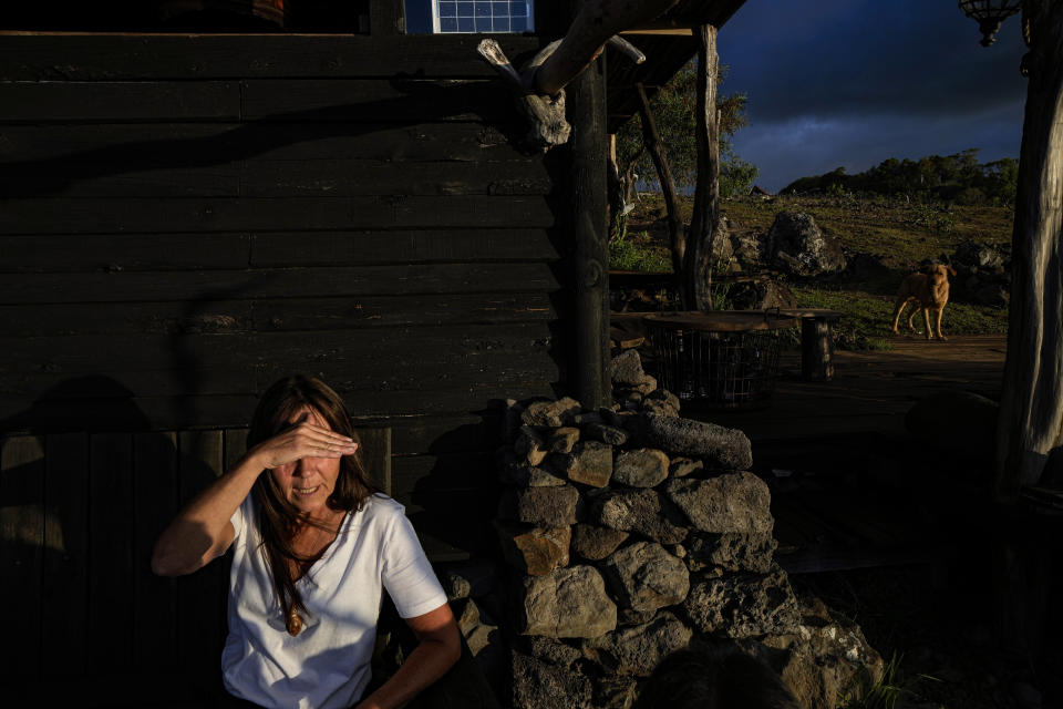 La artista de origen francés Delphine Poulain se cubre los ojos, sentada afuera de su casa mientras se pone el sol en Hanga Roa, Rapa Nui o Isla de Pascua, Chile, el miércoles 23 de noviembre de 2022. Poulain nació en París hace 52 años y ha estado enamorada de Rapa Nui desde que la visitó por primera vez en 1994.(AP Foto/Esteban Felix)