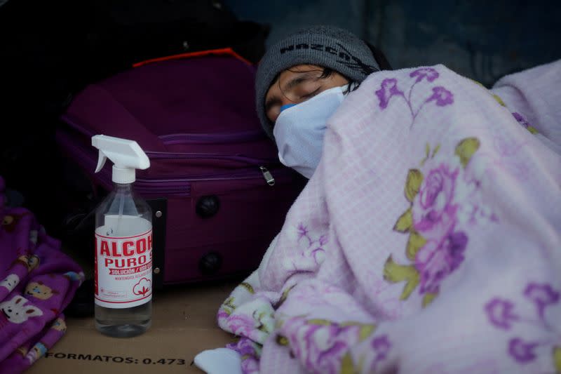 Un peruano duerme en la calle junto a una botella de alcohol desinfectante mientras espera que le hagan la prueba de la enfermedad por coronavirus (COVID-19) y le permiten regresar a su hogar en otra parte del país, en Lima, Perú.