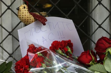 A note is seen with flowers placed outside the Dutch embassy in Moscow July 18, 2014. The note reads, "Forgive us!!!" REUTERS/Sergei Karpukhin