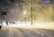 A man walks across a snow-covered road in the early morning with snowdrifts in Bielefeld, Germany, Sunday, Feb. 7, 2021. (Marcel Kusch/dpa via AP)