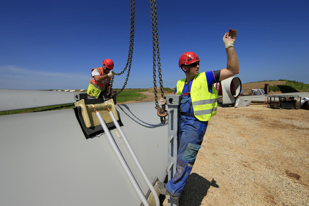 Employees work on a rotor blade of an E-70 wind turbine manufactured by German company Enercon for La Compagnie du Vent (GDF SUEZ Group) during its installation at a wind farm in Meneslies, Picardie region, July 17, 2014. France announced in July a package of tax breaks and low-cost loans to improve insulation in buildings and boost investment in renewable energy, which is supposed to provide 40 percent of the country's electricity by 2030. Picture taken July 17, 2014.  REUTERS/Benoit Tessier   (FRANCE - Tags: ENERGY BUSINESS CONSTRUCTION ENVIRONMENT)