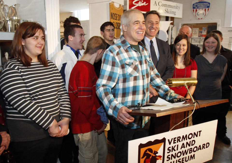 FILE - In this March 8, 2012, file photo, Jake Burton Carpenter, the creator of Burton Snowboards, center, speaks during a bill signing with Gov. Peter Shumlin, to the right of Burton, in Stowe, Vt. Shumlin signed a bill making skiing and snowboarding the official state sports of Vermont. Carpenter, the innovator who brought the snowboard to the masses and helped turn the sport into a billion-dollar business, has died after a recurring bout with cancer. He was 65. Officials from the company he founded, Burton Snowboards, told The Associated Press of his death Thursday, Nov. 21, 2019. (AP Photo/Toby Talbot, FIle)