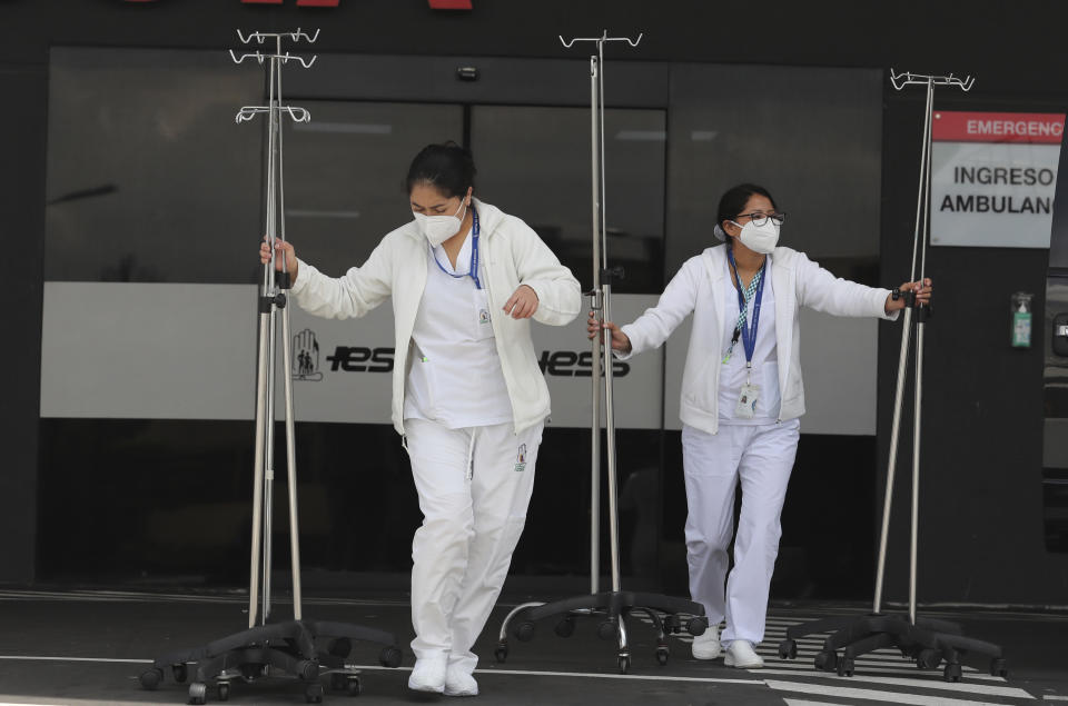 Enfermeras trasladan equipos médicos para instalar una carpa para tratar a pacientes con COVID-19 fuera del hospital del Instituto del Seguro Social debido al aumento de las nuevas infecciones por coronavirus en Quito, Ecuador, el martes 19 de enero de 2021. (AP Foto/Dolores Ochoa)