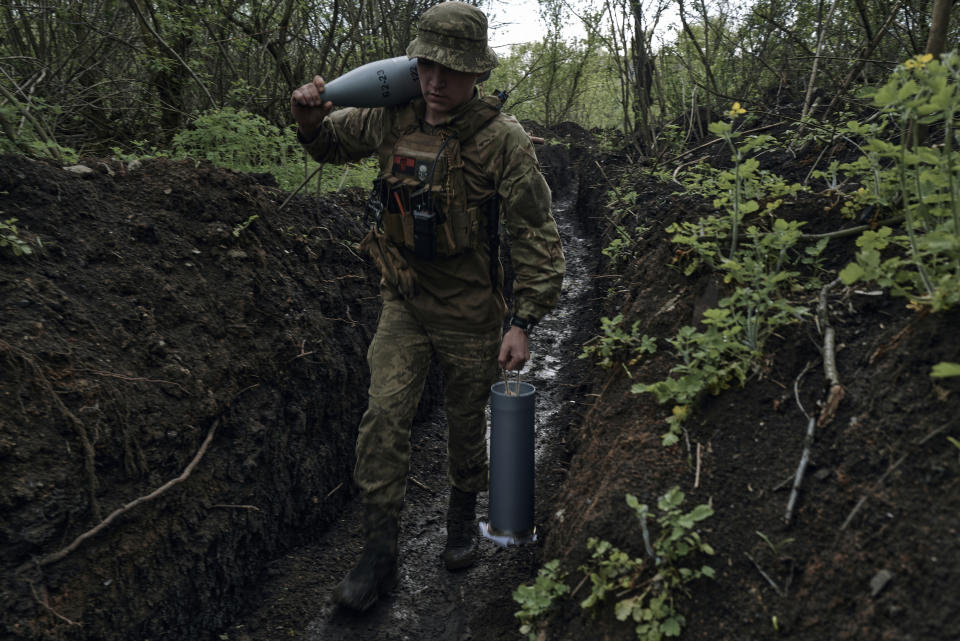 FILE- A Ukrainian soldier carries cannon shells in a trench near Bakhmut, an eastern city where fierce battles against Russian forces have been taking place, in the Donetsk region, Ukraine, Saturday, April 29, 2023. Ukrainian President Volodymyr Zelenskyy said Sunday, May 21, 2023 that Russian forces weren't occupying Bakhmut, casting doubt on Moscow's insistence that the eastern Ukrainian city had fallen. The fog of war made it impossible to confirm the situation on the ground in the invasion’s longest battle, and the comments from Ukrainian and Russian officials added confusion to the matter. (AP Photo/Libkos, File)