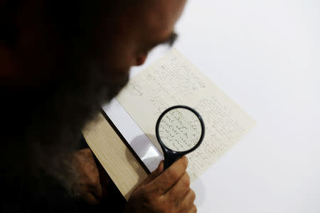 Meron Eren of Kedem Auction House uses a magnifying glass to look at a letter handwritten by composer Richard Wagner in 1869, before it is sold at an auction in Jerusalem, April 24, 2018. REUTERS/Ammar Awad