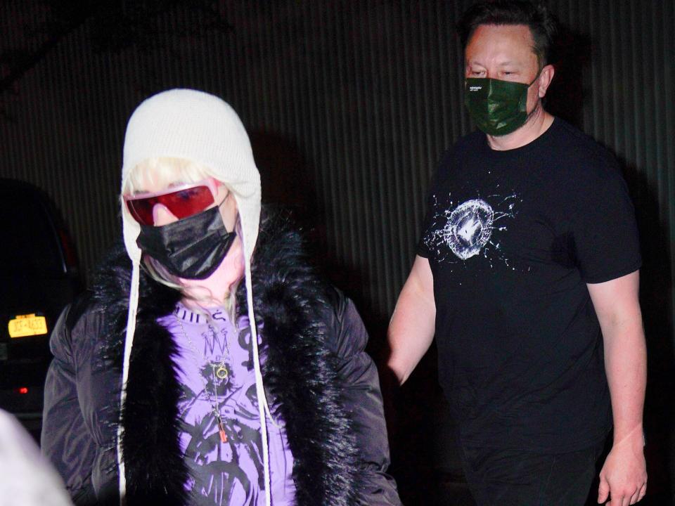 Grimes and Elon Musk wearing masks and walking to a car in New York City