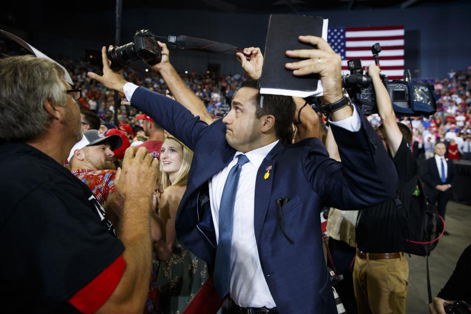 ADDS THAT MAN BLOCKING CAMERA IS A VOLUNTEER - A volunteer member of the advance team for President Donald Trump blocks a camera as a photojournalist attempts to take a photo of a protester during a campaign rally at the Ford Center, Thursday, Aug. 30, 2018, in Evansville, Ind. (AP Photo/Evan Vucci)