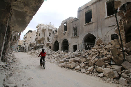 A boy rides a bicycle near damaged buildings in the rebel held area of Old Aleppo, Syria May 5, 2016. REUTERS/Abdalrhman Ismail