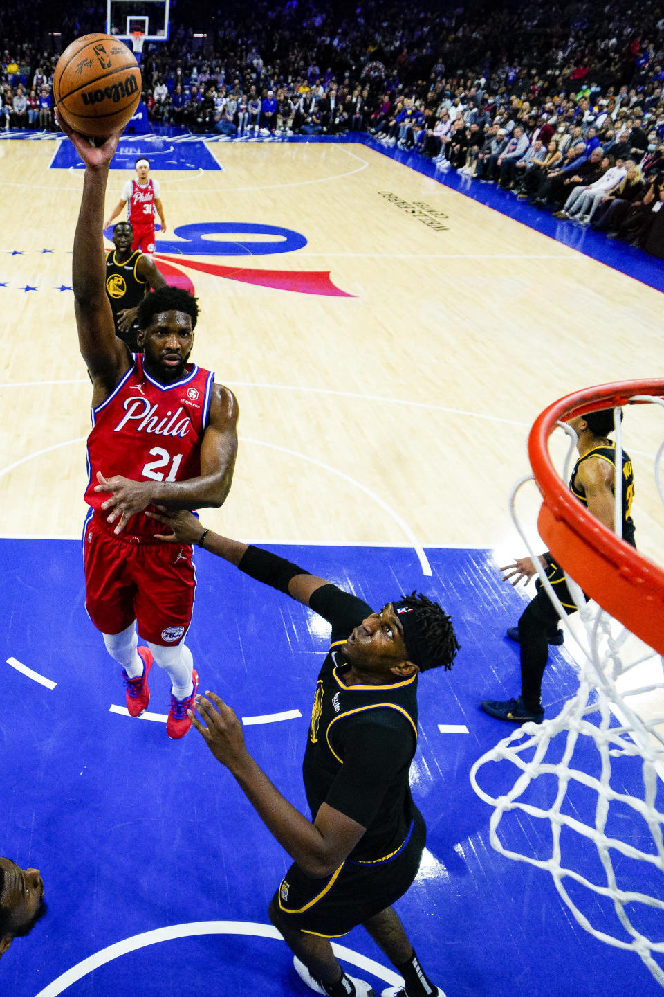 Philadelphia 76ers' Joel Embiid, left, shoots over Golden State Warriors' Kevon Looney, right, during the first half of an NBA basketball game, Saturday, Dec. 11, 2021, in Philadelphia. (AP Photo/Chris Szagola)