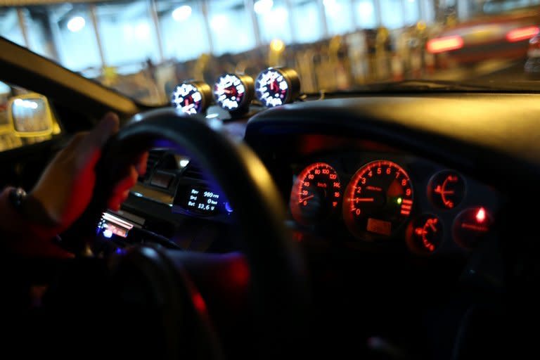 A driver places his hand on the steering wheel on his modified racing car before a race in Hong Kong, on April 7, 2013. As night begins to give way to dawn, 40 high-performance cars pull up on an empty Hong Kong backstreet. Their revving engines fill the air with a heavy smell of petrol as the city sleeps