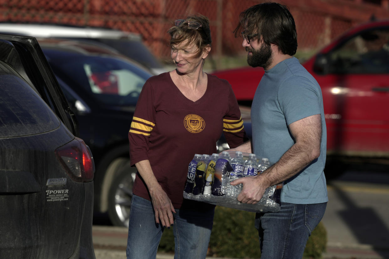 Becky Rance, center, and Waddle Colley hand out water in downtown East Palestine, Ohio, as the cleanup of portions of a Norfolk Southern freight train that derailed over a week ago continues, Wednesday, Feb. 15, 2023. (AP Photo/Gene J. Puskar)