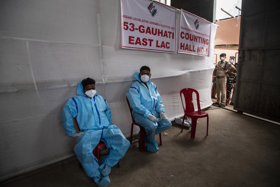 Counting agents in protective suits take rest during the counting of votes of Assam state assembly election in Gauhati, India, Sunday, May 2, 2021. With Indian hospitals struggling to secure a steady supply of oxygen, and more COVID-19 patients dying amid the shortages, a court in New Delhi said it would start punishing government officials for failing to deliver the life-saving items. (AP Photo/Anupam Nath)