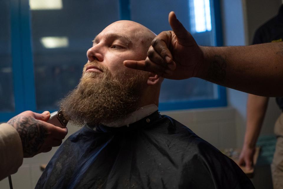 James Wheeler, center, sits in a barber chair as Amier Hill, right, points out an area for Eryn Carver, left, to keep an eye on while trimming Wheeler's beard in front of a small group of incarcerated men during a one-hour hands-on barber course as part of the I.G.N.I.T.E. (Inmate Growth Naturally and Intentionally Through Education) program held on the fifth floor of the Genesee County Jail in Flint on Thursday, Jan. 4, 2024.