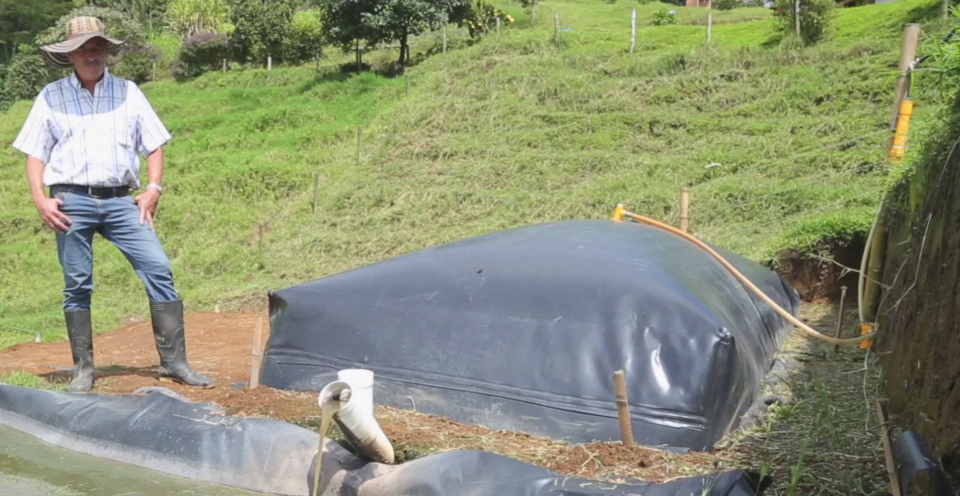 Un granjero en su finca juto a uno de los biodigestores fabricados e instalados por Sistema.Bio. Imagen: cortesía de Sistema.Bio.