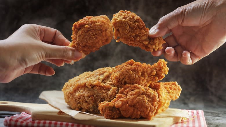 hands holding fried chicken