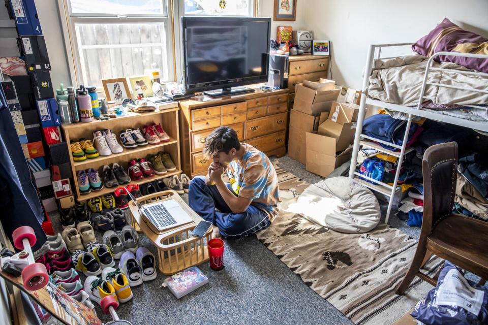 A teenage boy watches a lecture on his laptop computer.