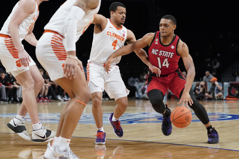 North Carolina State's Casey Morsell (14) drives against Clemson Tigers' Nick Honor (4) during the first half of an NCAA college basketball game of the Atlantic Coast Conference men's tournament, Tuesday, March 8, 2022, in New York. (AP Photo/John Minchillo)