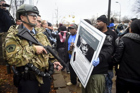 A protester carries a sign as police stand their ground in front of a north Minneapolis police precinct during a protest in response of Sunday's shooting death of Jamar Clark by police officers in Minneapolis, Minnesota, November 18, 2015. REUTERS/Craig Lassig