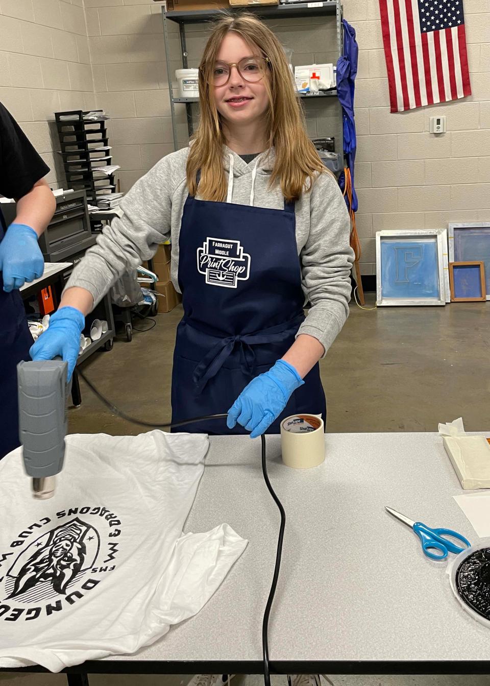 Student Bennett McKinney dries her T-shirt creation with a paint drying tool in the print shop of Farragut Middle School on March 20, 2024.