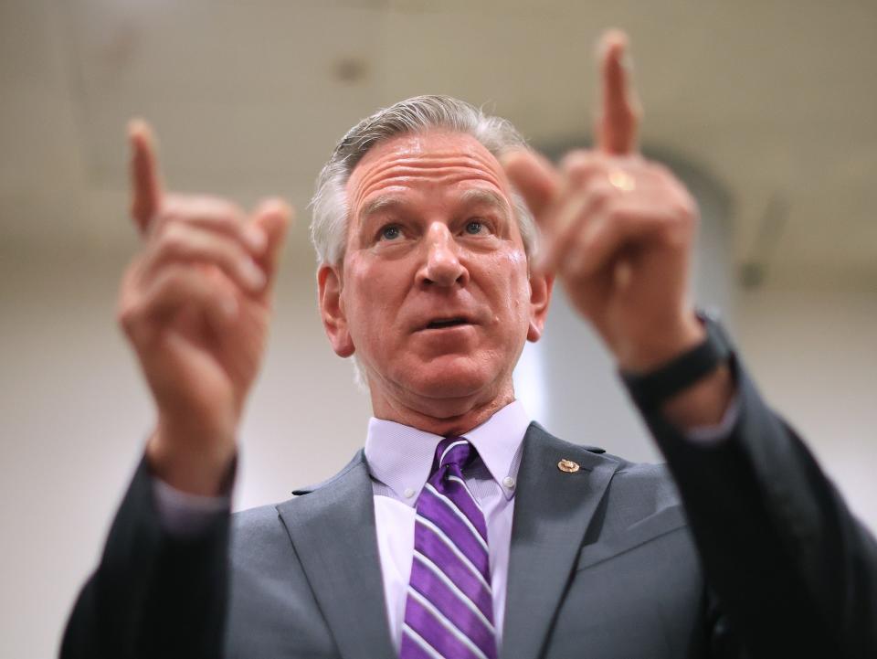 Sen. Tommy Tuberville, an Alabama Republican, is pointing while wearing a gray suit and purple tie.