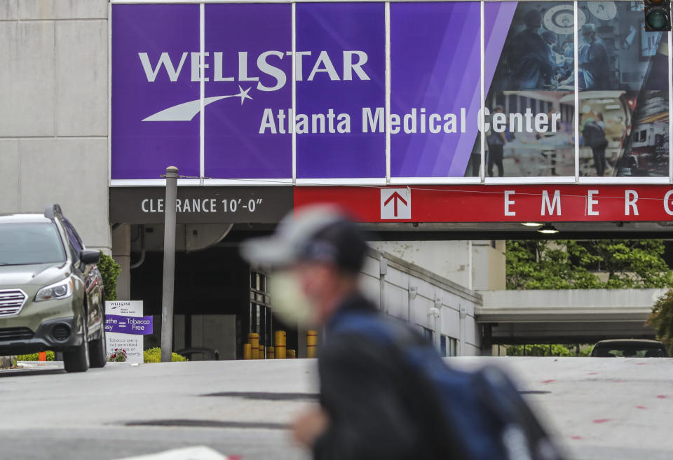 FILE - A masked man passes Wellstar Atlanta Medical Center in Atlanta, May 20, 2020. A group of Democrats and the NAACP said Wednesday, March 8, 2023, that they had filed complaints with the federal government that Wellstar Health System violated federal anti-discrimination laws and its nonprofit status when it closed the Atlanta hospital in 2022, citing losses. (John Spink/Atlanta Journal-Constitution via AP, File)