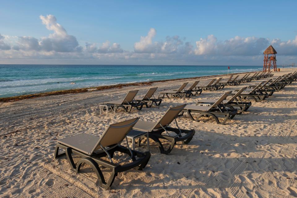 In this June 11, 2020  photo, lounge chairs fill an empty beach in Cancun, Mexico.