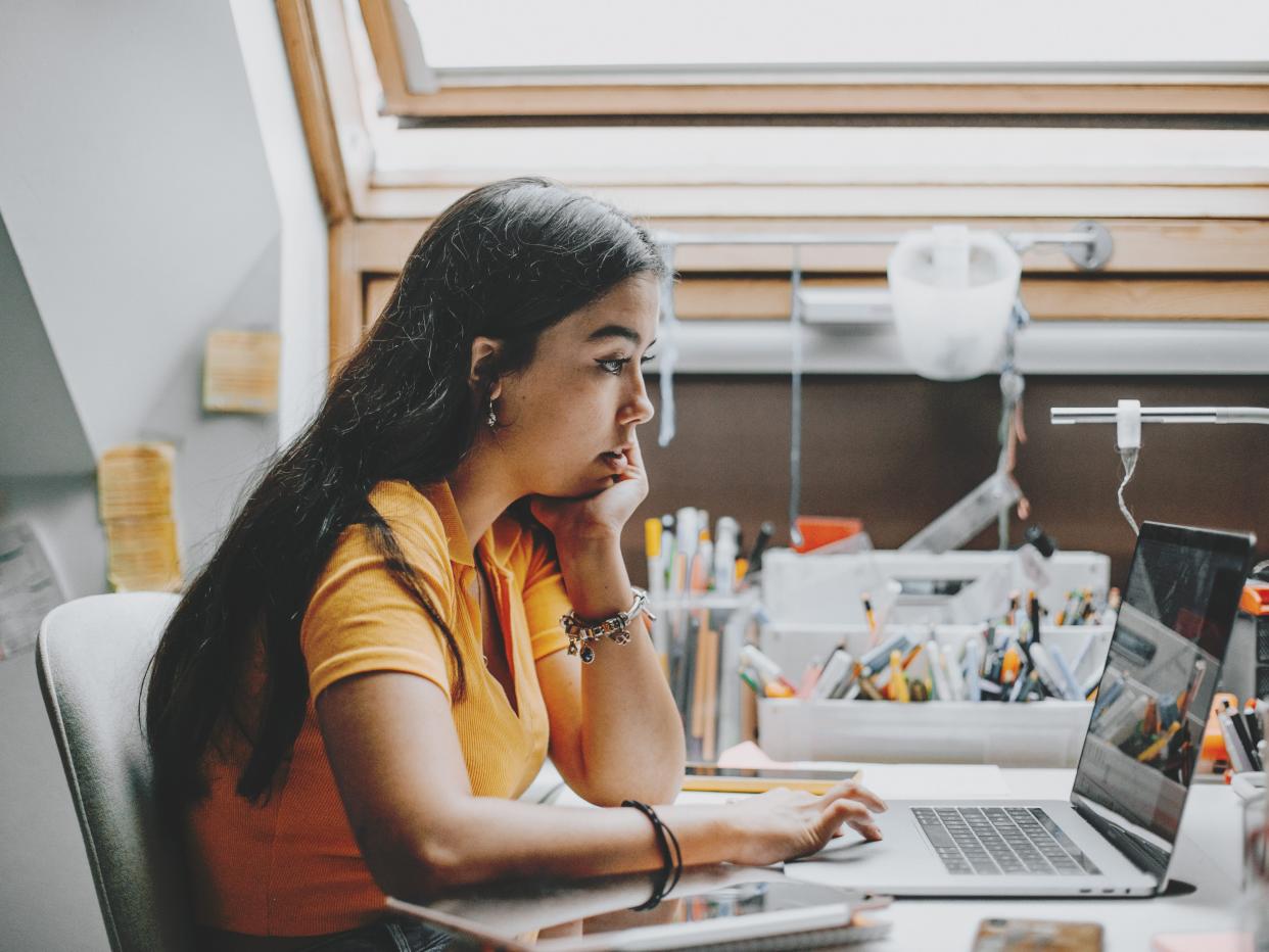 Hispanic young woman working and studying from home using laptop