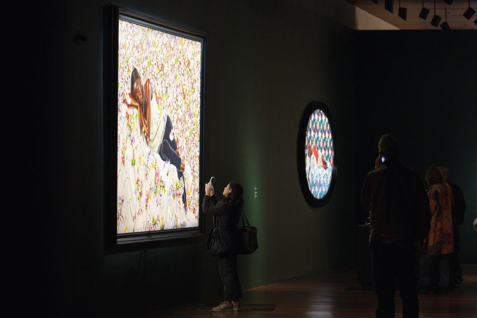 A woman takes a picture of a painting by Kehinde Wiley titled "Morpheus," at the de Young Museum in San Francisco, Friday, March 24, 2023. The painting is part of the "Kehinde Wiley: An Archaeology of Silence," exhibition. (AP Photo/Godofredo A. Vásquez)