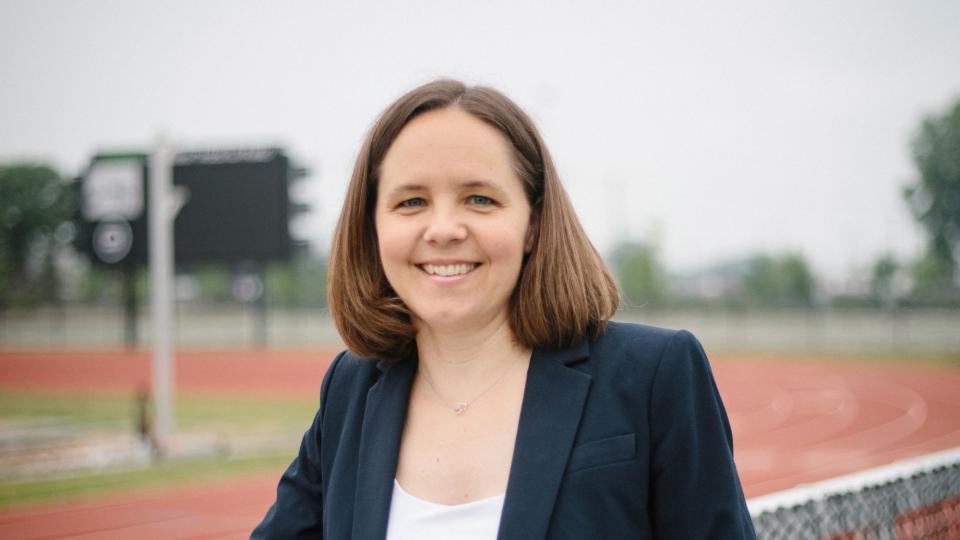 a person standing along fence outside of track