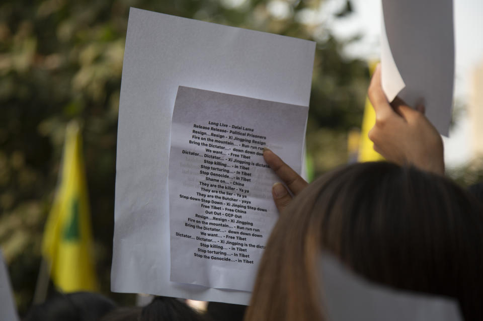 An exile Tibetan activist reads slogans written on a piece paper holding against a white blank sheet, during a protest in New Delhi, India, Friday, Dec. 2, 2022. Over 100 Tibetan exiles held up blank white papers as they congregated in the Indian capital on Friday to express solidarity with protesters in China and their anger over Beijing’s “zero-COVID” policy. The blank white paper is a symbol of defiance against the ruling Communist party’s pervasive censorship. (AP Photo/Bhumika Saraswati) ,