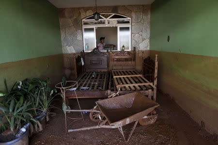 A man works on the cleaning of a house flooded with mud after a dam, owned by Vale SA and BHP Billiton Ltd burst, in Barra Longa, Brazil, November 7, 2015. REUTERS/Ricardo Moraes