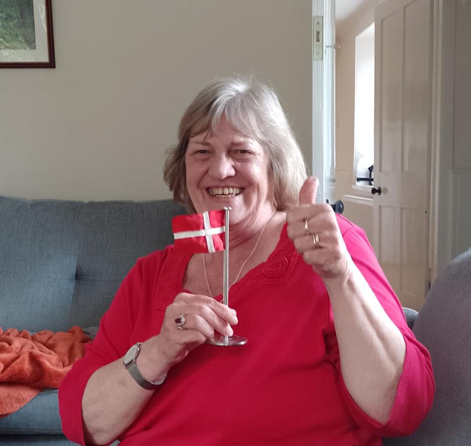 Elderly woman smiling and holding a small Danish flag after watching the England v Denmark Euro match