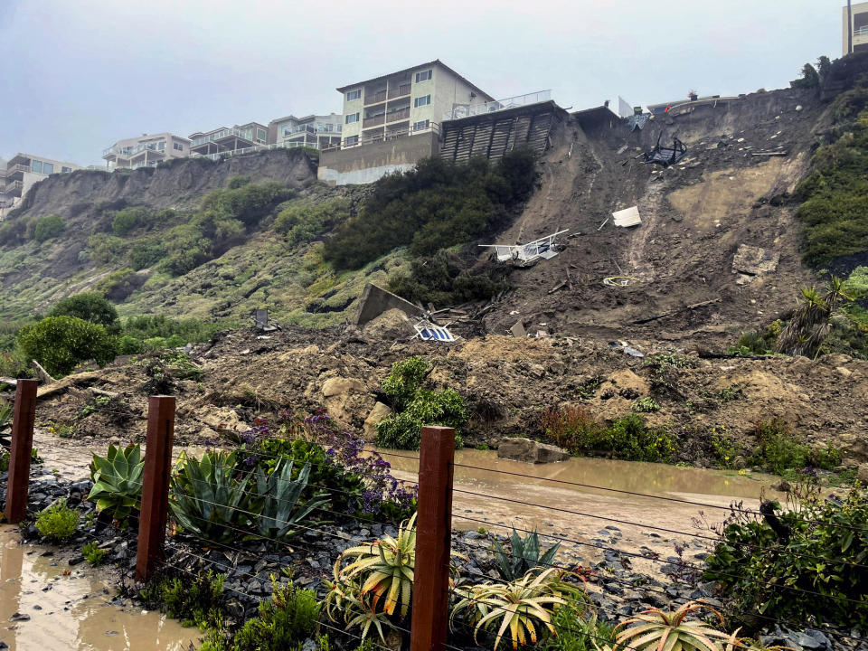 In this image provided by the Orange County Fire Authority, debris lines cliff where three apartment structures had to be evacuated due to a landslide in San Clemente, Calif., Wednesday, March 15, 2023. California's 11th atmospheric river of the winter has taken parting shots at southern counties as it moves out after walloping the storm-battered state. A landslide in coastal San Clemente has forced evacuation of four hilltop apartment buildings. (Orange County Fire Authority via AP)