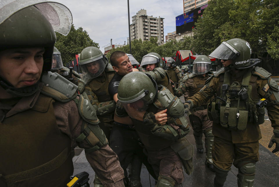 A demonstrator is detained by the police during a protest in Santiago, Chile, Saturday, Oct. 19, 2019. The protests started on Friday afternoon when high school students flooded subway stations, jumping turnstiles, dodging fares and vandalizing stations as part of protests against a fare hike, but by nightfall had extended throughout Santiago with students setting up barricades and fires at the entrances to subway stations, forcing President Sebastian Pinera to announce a state of emergency and deploy the armed forces into the streets. (AP Photo/Esteban Felix)