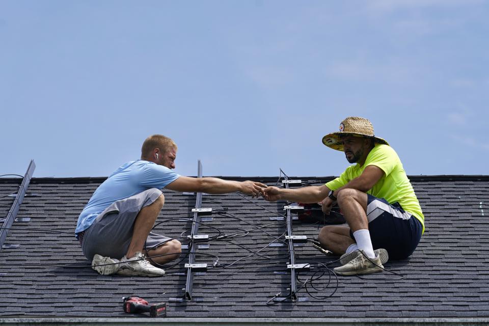 Brian Hoeppner, left, and Even Berrios, install a solar panel on the roof of a home in Frankfort, Ky., Monday, July 17, 2023. Since passage of the Inflation Reduction Act, it has boosted the U.S. transition to renewable energy, accelerated green domestic manufacturing, and made it more affordable for consumers to make climate-friendly purchases, such as installing solar panels on their roofs. (AP Photo/Michael Conroy)