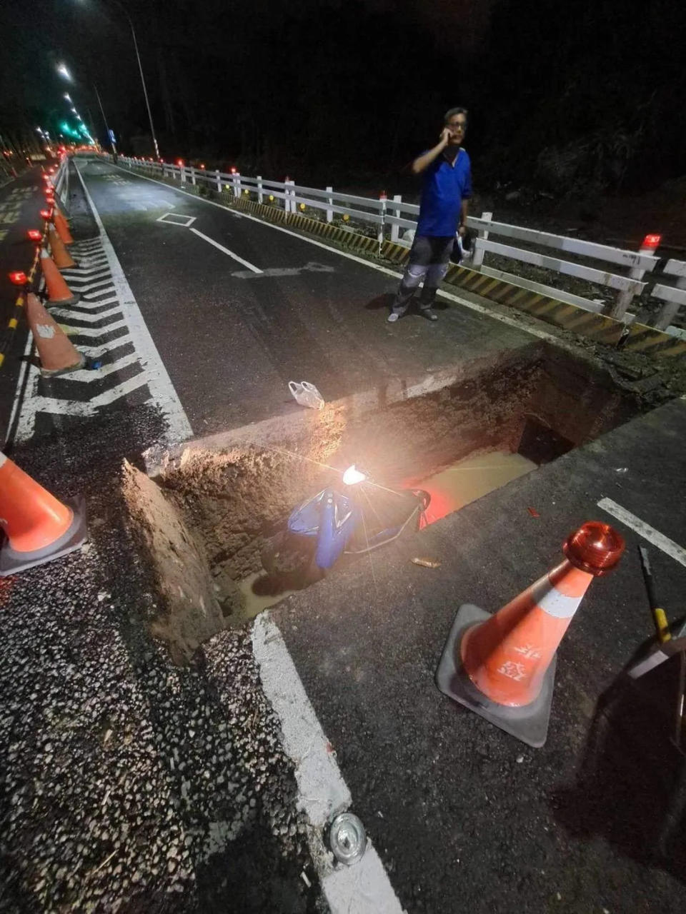 <strong>裂出的大鴻溝生吞整台機車，由於連日大雨，洞底還浸泡黃色滾滾泥水。（圖／民眾提供）</strong>