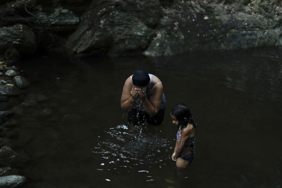 Liz Vargas and her niece Camila Vargas bathe on the skirt of a mountain in Avila National Park in Caracas, Venezuela, Thursday, April 4, 2019. Vargas said she hasn't had running water at home for the previous 15 days, and this was the first time she'd come to bathe where she used to swim for fun. (AP Photo/Natacha Pisarenko)