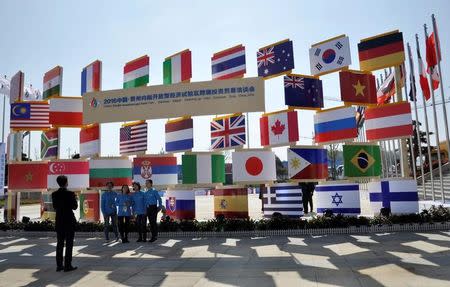 People stand near signboards of a cross-border investment and trade fair in Guiyang, Guizhou Province, China, November 10, 2016. Picture taken November 10, 2016. REUTERS/Shu Zhang