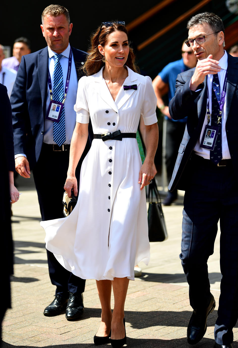 Kate attended day two of Wimbledon, wearing a white<a href="https://www.suzannah.com/products/flippy-wiggle-dress" rel="nofollow noopener" target="_blank" data-ylk="slk:button-up dress by Suzannah;elm:context_link;itc:0;sec:content-canvas" class="link "> button-up dress by Suzannah</a>, with an Alexander McQueen bow detail belt and her Gianvito Rossi 'Piper' heels. A new raffia satchel by Alexander McQueen, her Catherine Zoraida earrings and a pair of Ray-Ban Wayfarers completed her courtside look. [Photo: PA]