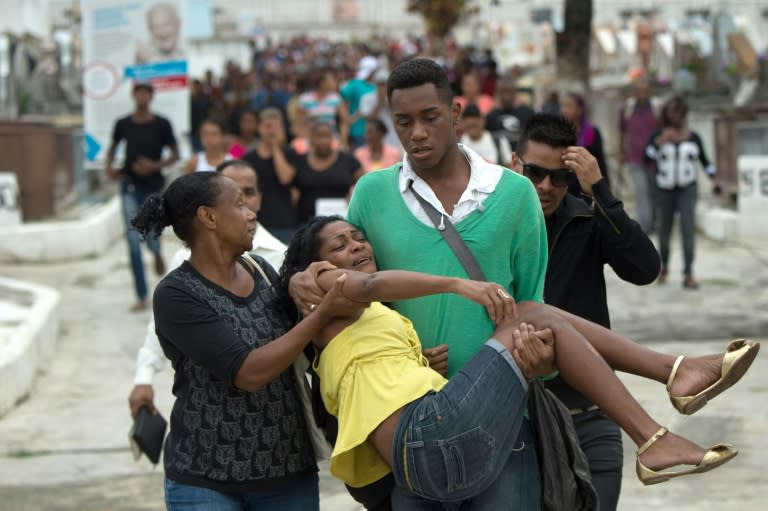 A woman is carried away from the cemetery at the end of the funeral of Wesley Castro Rodrigues, 25, killed with four other friends last Satuday by policemen who shot 50 times at their car, in Rio de Janeiro, Brazil, on November 30, 2015