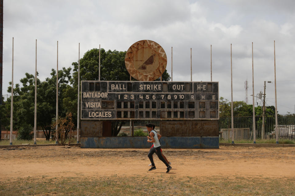 Teenagers run in front of an old baseball scoreboard in Los Ninos Cantores stadium in Maracaibo, Venezuela. (Photo: Manaure Quintero/Reuters)