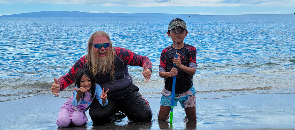 Jason Rosenbloom (pictured in center) poses with kids on the beach.