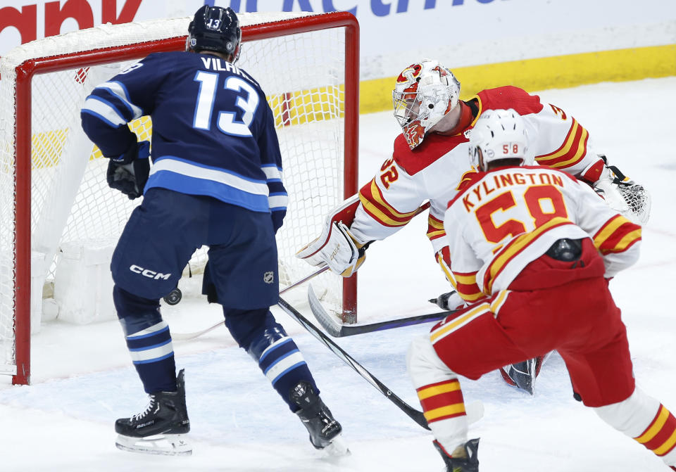 Winnipeg Jets' Gabriel Vilardi (13) scores on Calgary Flames goaltender Dustin Wolf (32) as Oliver Kylington (58) defends during the first period of an NHL hockey game Thursday, April 4, 2024, in Winnipeg, Manitoba. (John Woods/The Canadian Press via AP)