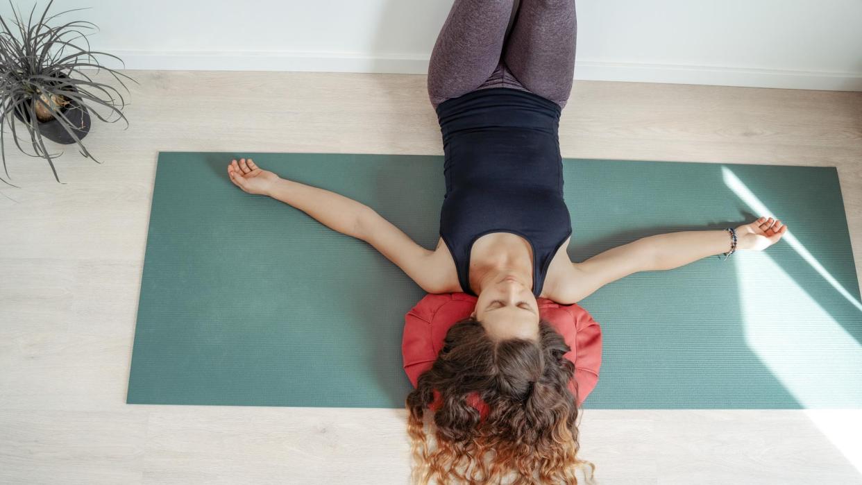  Woman performing a wall Pilates workout at home. 